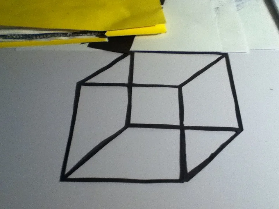 Drawing of a 3D cube on a white surface.