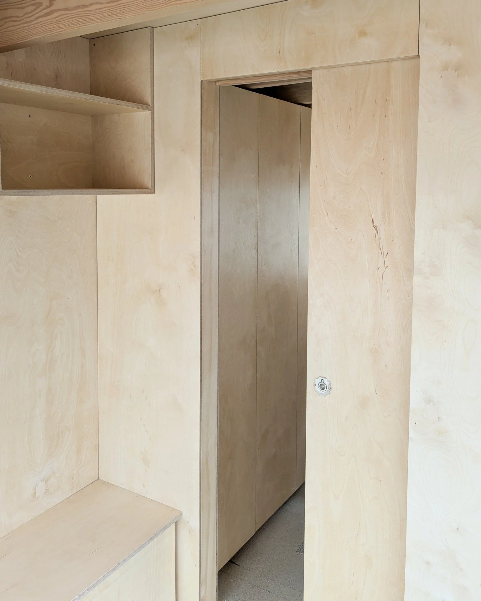 A closer look at the custom birch plywood interior and furniture inside this garden cabin. It features shadow gap details and a built-in birch plywood pocket door that separates the dedicated office area from the utility room, all complemented by exp