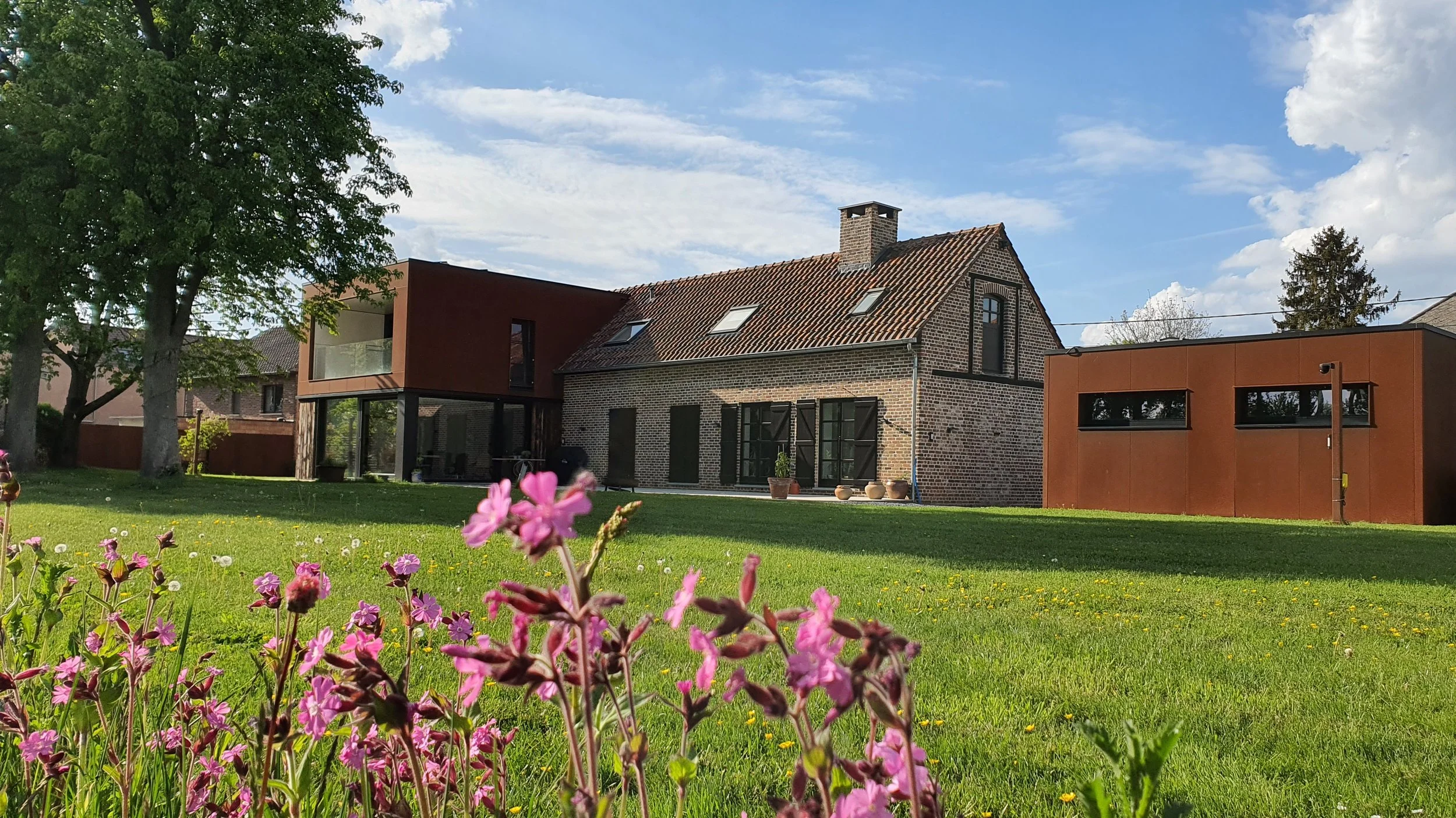 A modern house with wood and cortensteel exterior walls, large windows.
