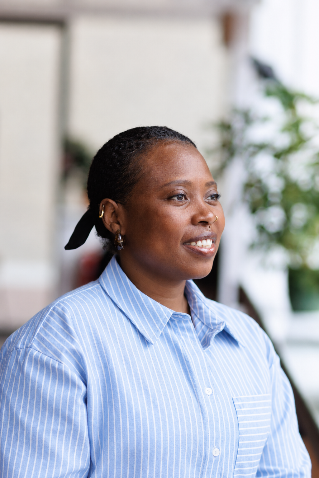 Isioma Daniel smiling and looking to the side, wearing a blue and white striped shirt.