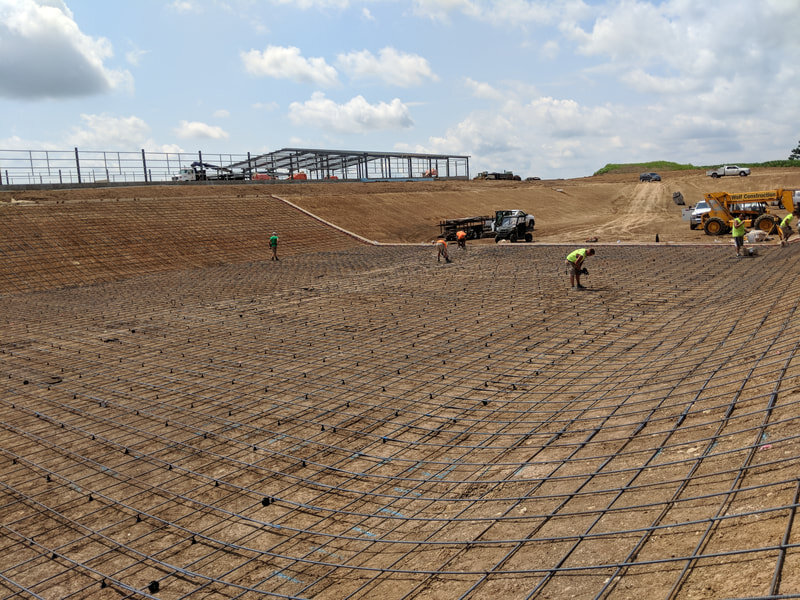 Rebar Installation Inside the Proposed Waste Storage Basin. Beginning Construction of the Freestall Barn in the Background.
