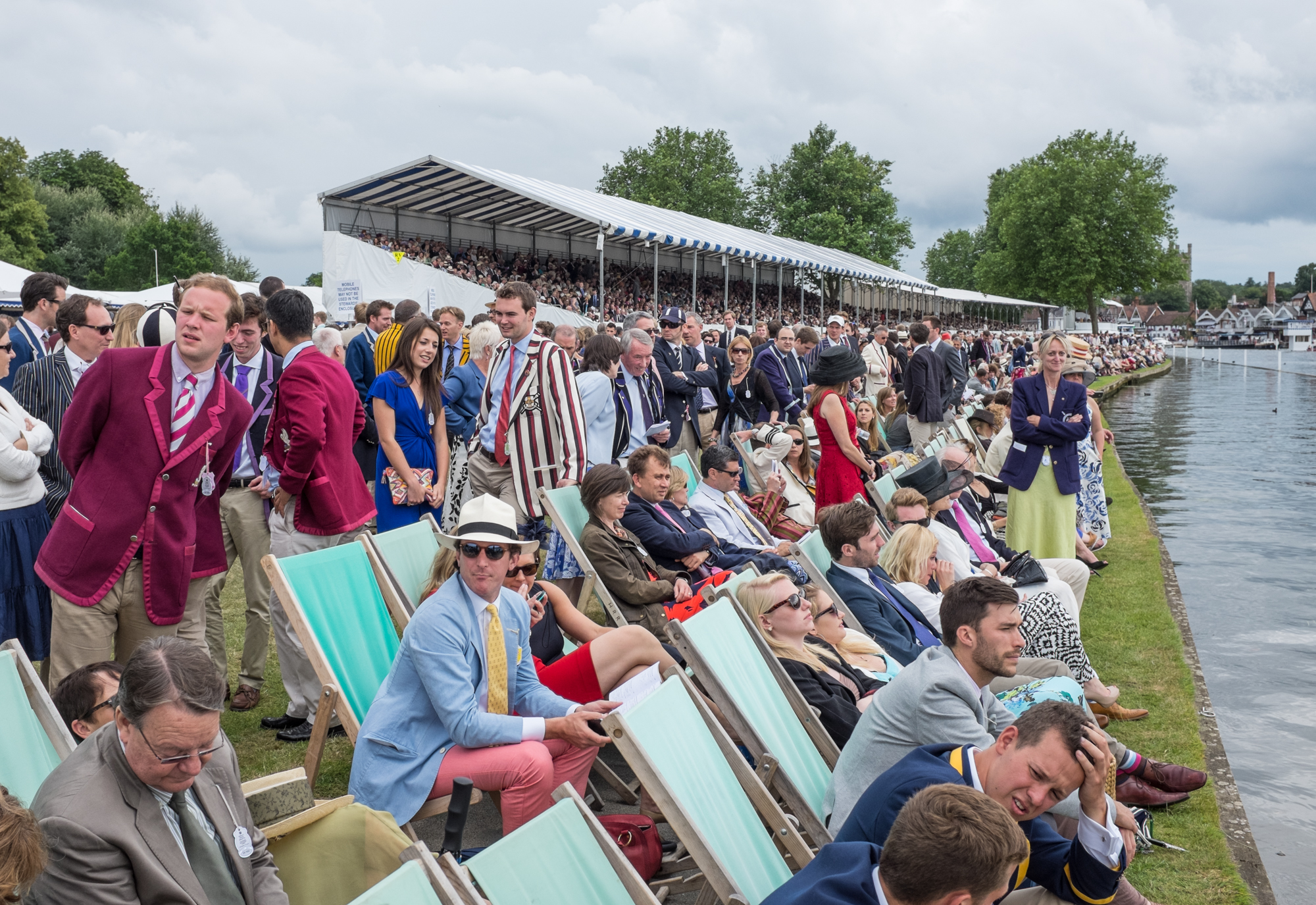  Spectators in the Steward's Enclosure line the banks at Henley Royal Regatta. A strict dress code applies: Jacket and tie for men, skirts or dresses below the knee for women. 