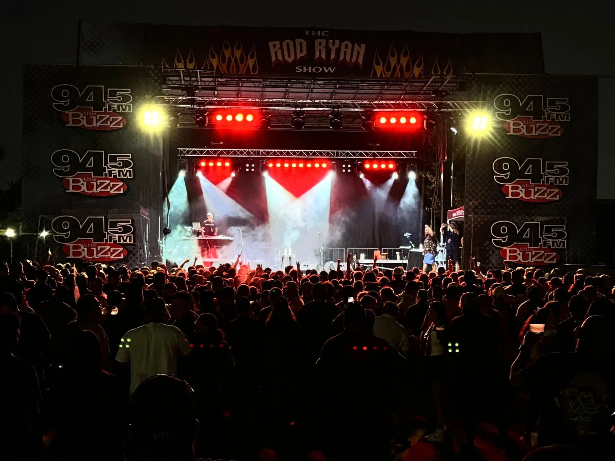 94.5 FM The Buzz Concert-style stage with bold red and white lighting inside a packed venue, perfect for seasonal shows, performances, or branded entertainment events.
