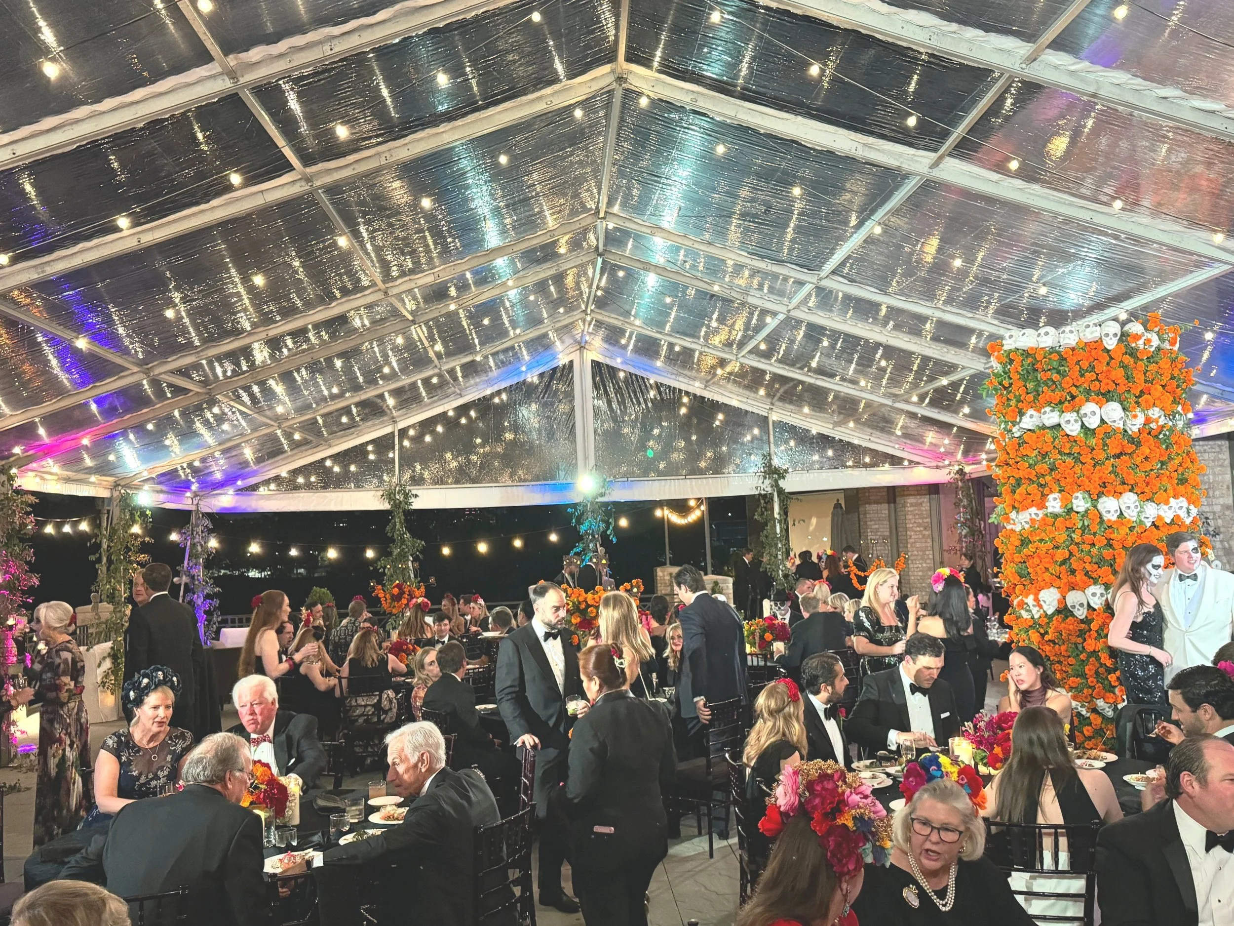 Guests at a formal celebration dinner inside a decorated tent, with floral arrangements and string lights. Ideal for showcasing WBSAV’s AV capabilities in large social gatherings.