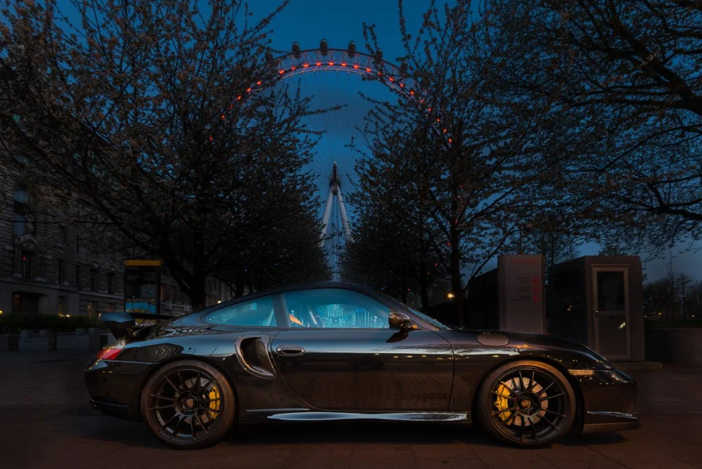 Porsche 996 parked at night with the London Eye in the background.