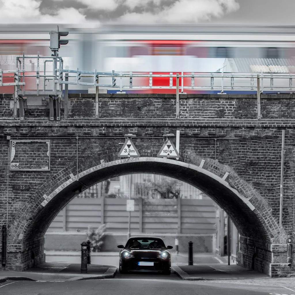 Porsche 996 driving under the arches of London Underground whilst a train passes overhead