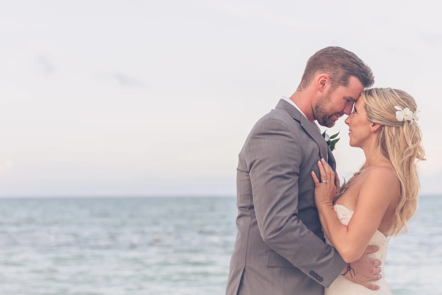 The bride and groom hug on the edge of the ocean in Jamaica