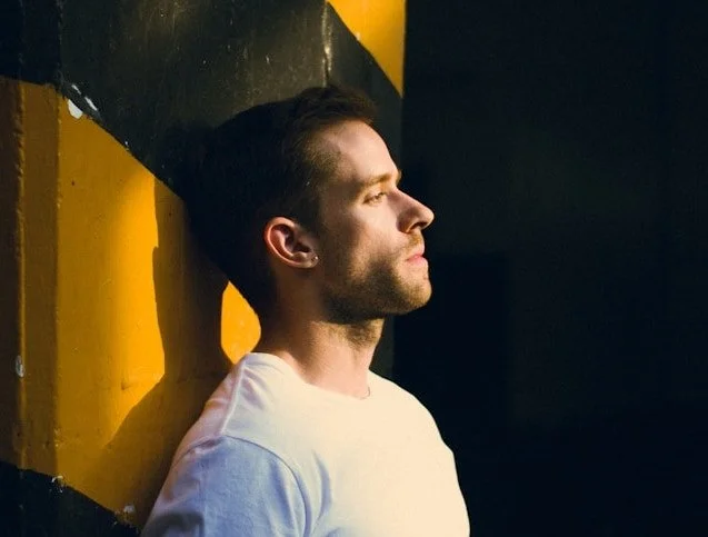 A man looking away against a yellow pole