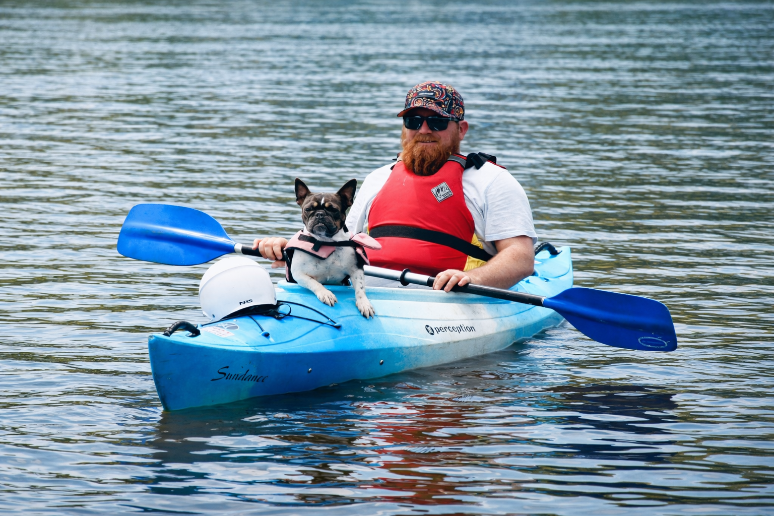 Man and dog kayaking on tranquil water.png
