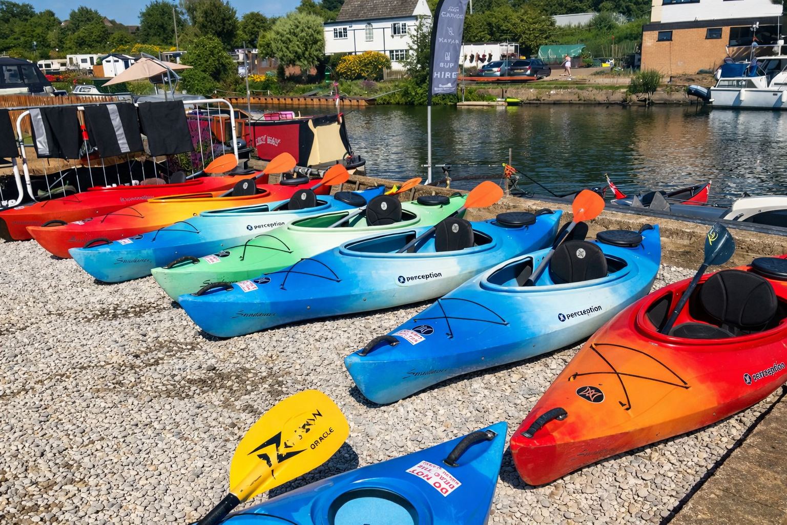 Colourful kayaks by the riverbank.png