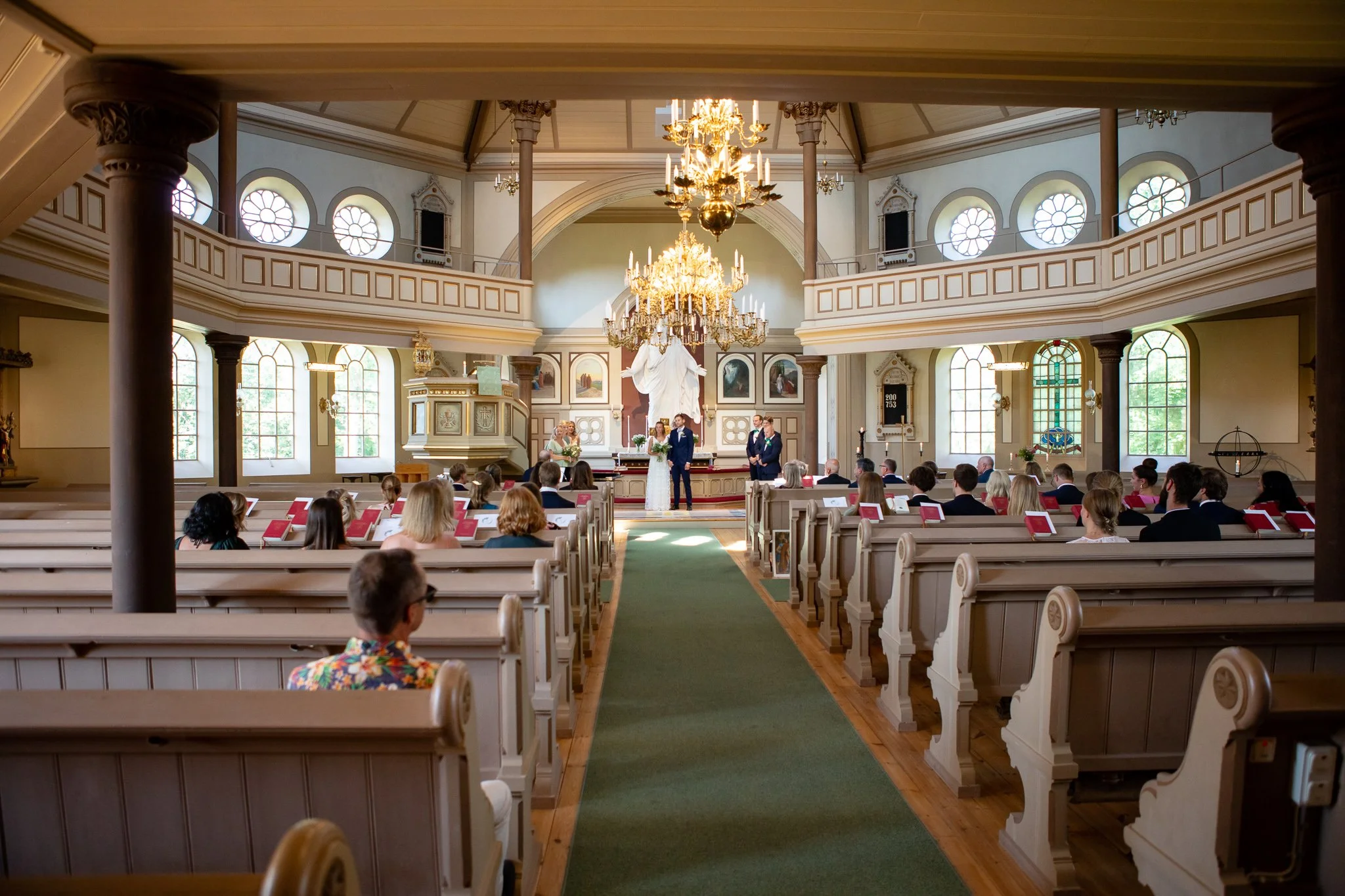 En kyrka med höga fönster, kristallkronor med brudparet och gäster i Västervik