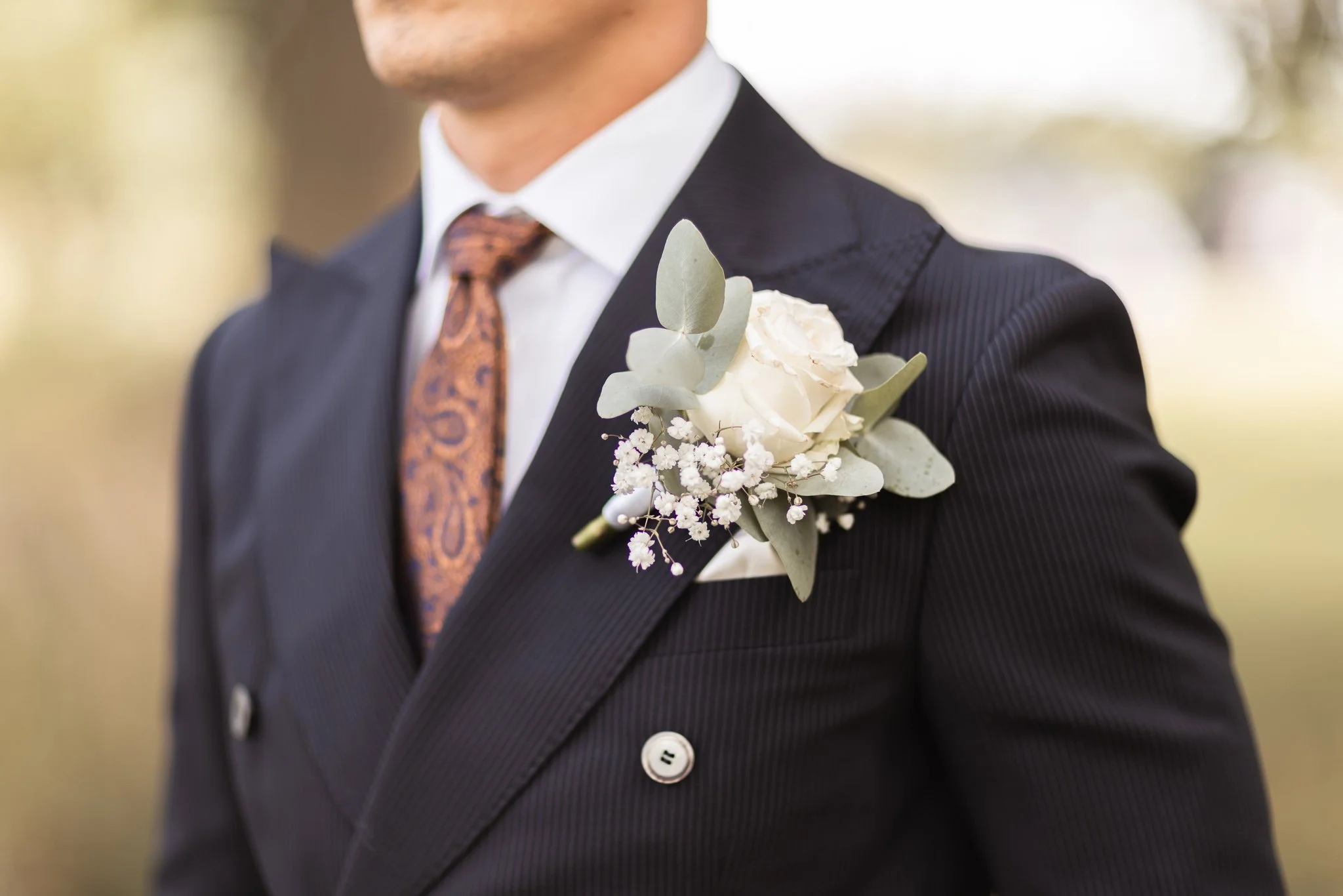 Brudgums detaljer med blommor i bröstet ståtlig slips taget vid Olais Ladda. Bröllopsfotograf i Linköping Östergötland