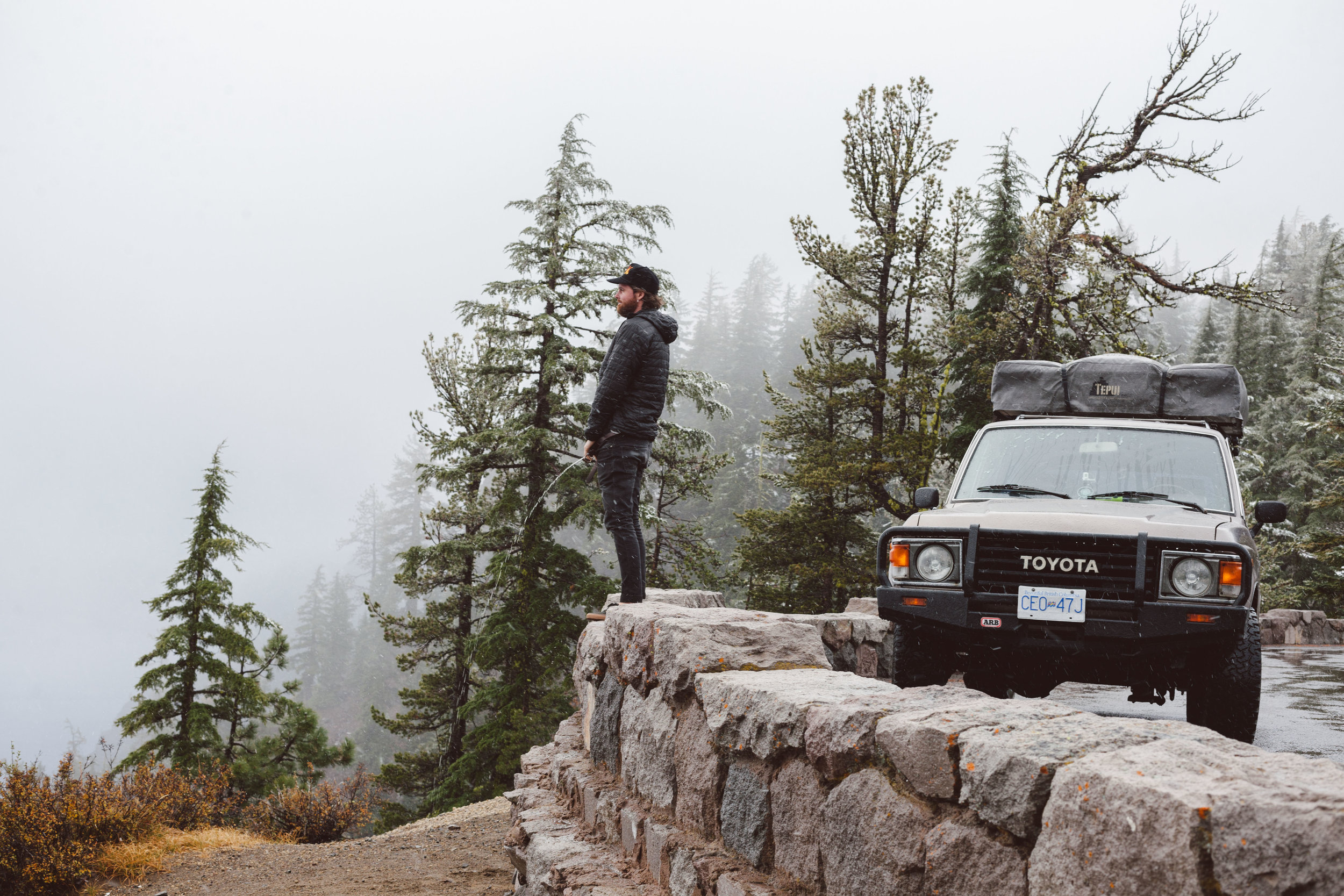 Graham taking a piss looking towards a snowy crater lake