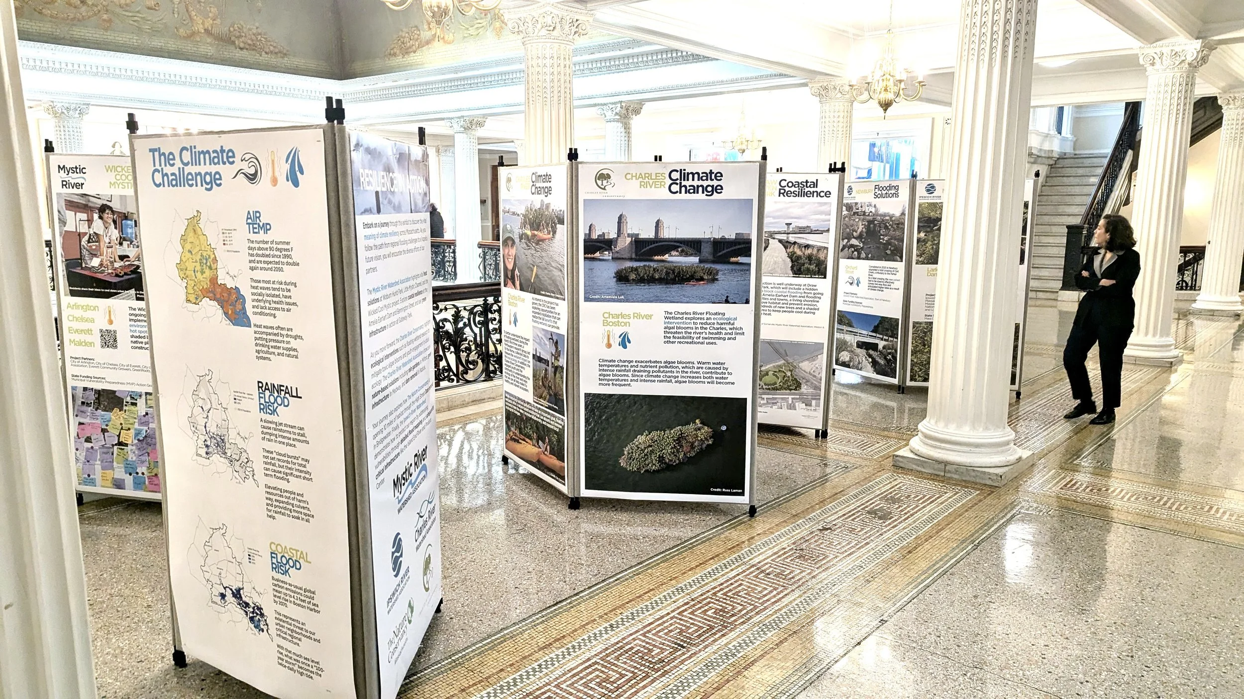 A person walks through several poster displays at the MA Statehouse.