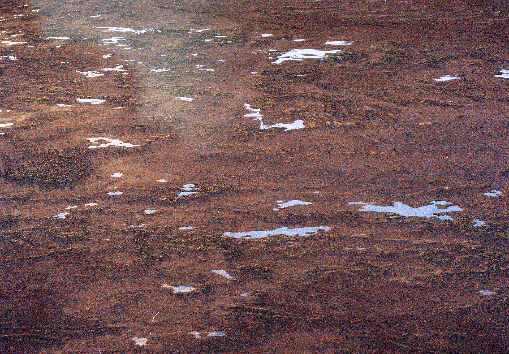 After Rain Taken from the air, not long after two days of rain, the contrasting pools of water reflect the sky against the damp red sand. These are the vast plains between Lake Eyre and the smallest town in Australia, William Creek. 