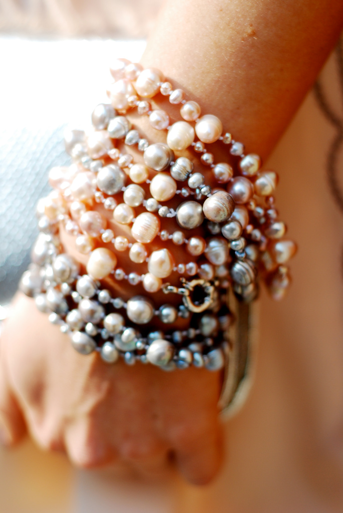 Multiple pearl bracelets stacked on a person's wrist.