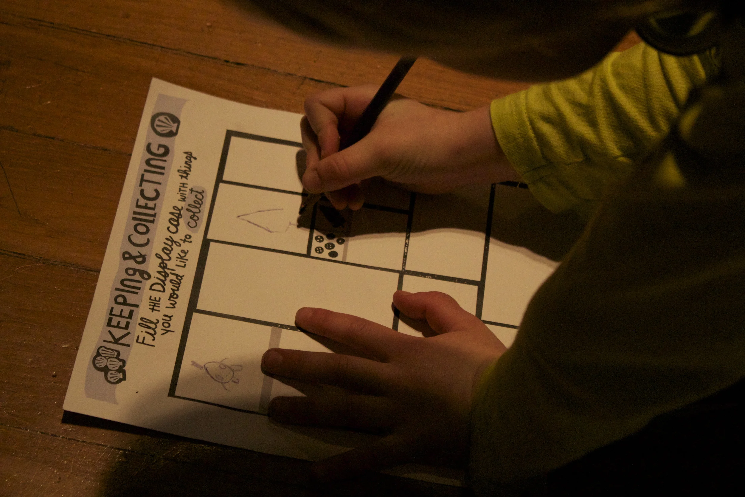 A young visitor takes a moment to draw on the 'Keeping and Collecting' worksheet at the 'Discoveries' exhibition