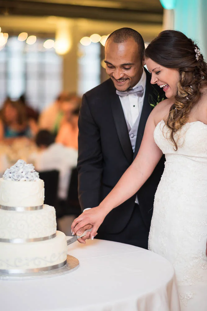 A bride and groom cut their cake during their summer wedding at Windows on Washington.
