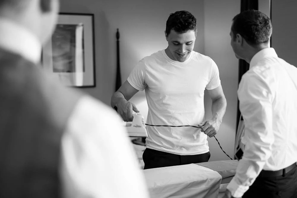 Groomsmen joke as they get ready for a summer wedding. 