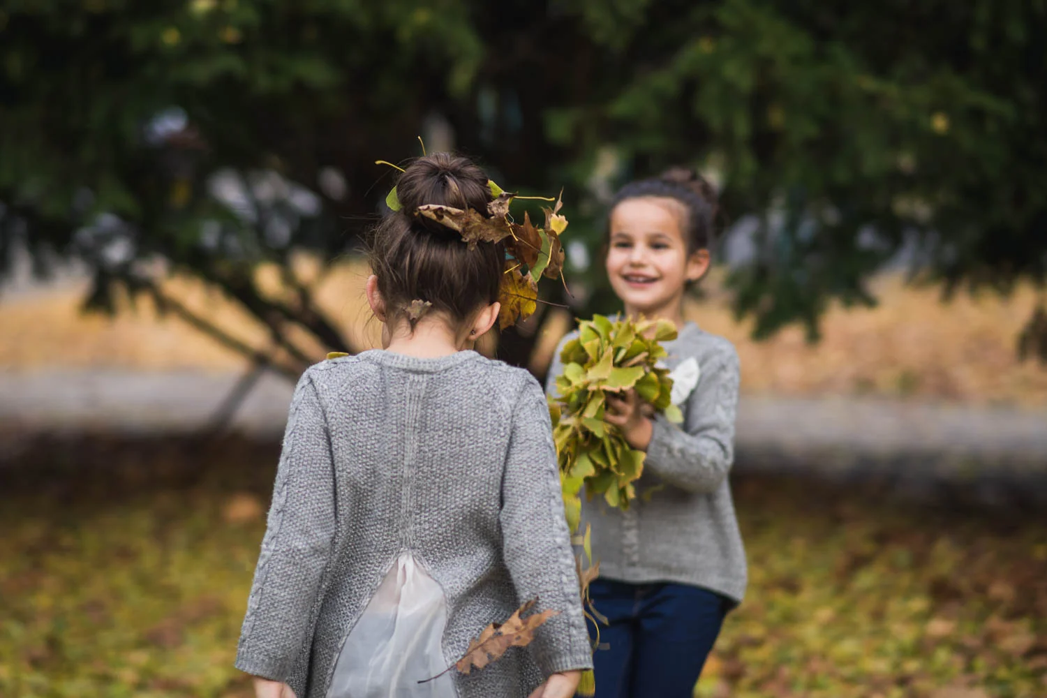 A portrait of kids throwing leaves during their fall family photography mini session at Tower Grove Park. 