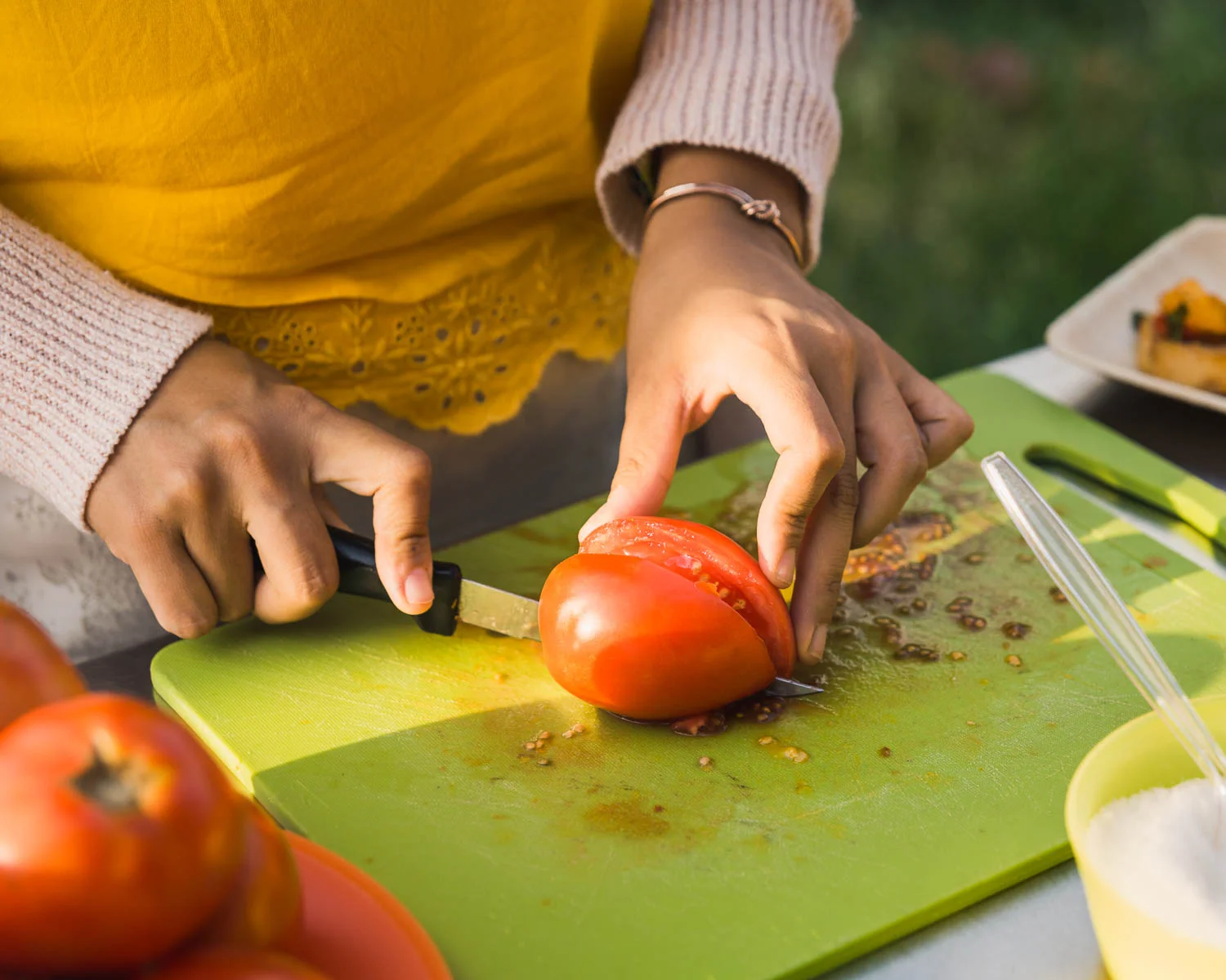 A volunteer chops into tomatoes for participants at the Tomato Party at Common Good City Farm.
