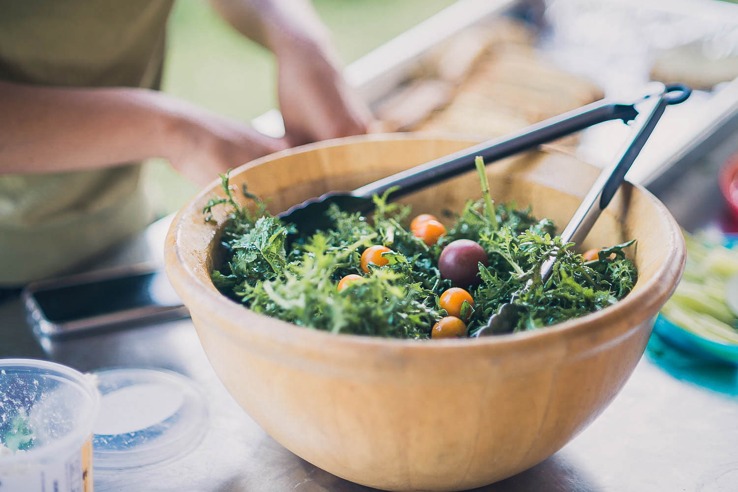 A volunteer at Common Good City Farm adds tomatoes to a salad at a family dinner on July 19, 2018.