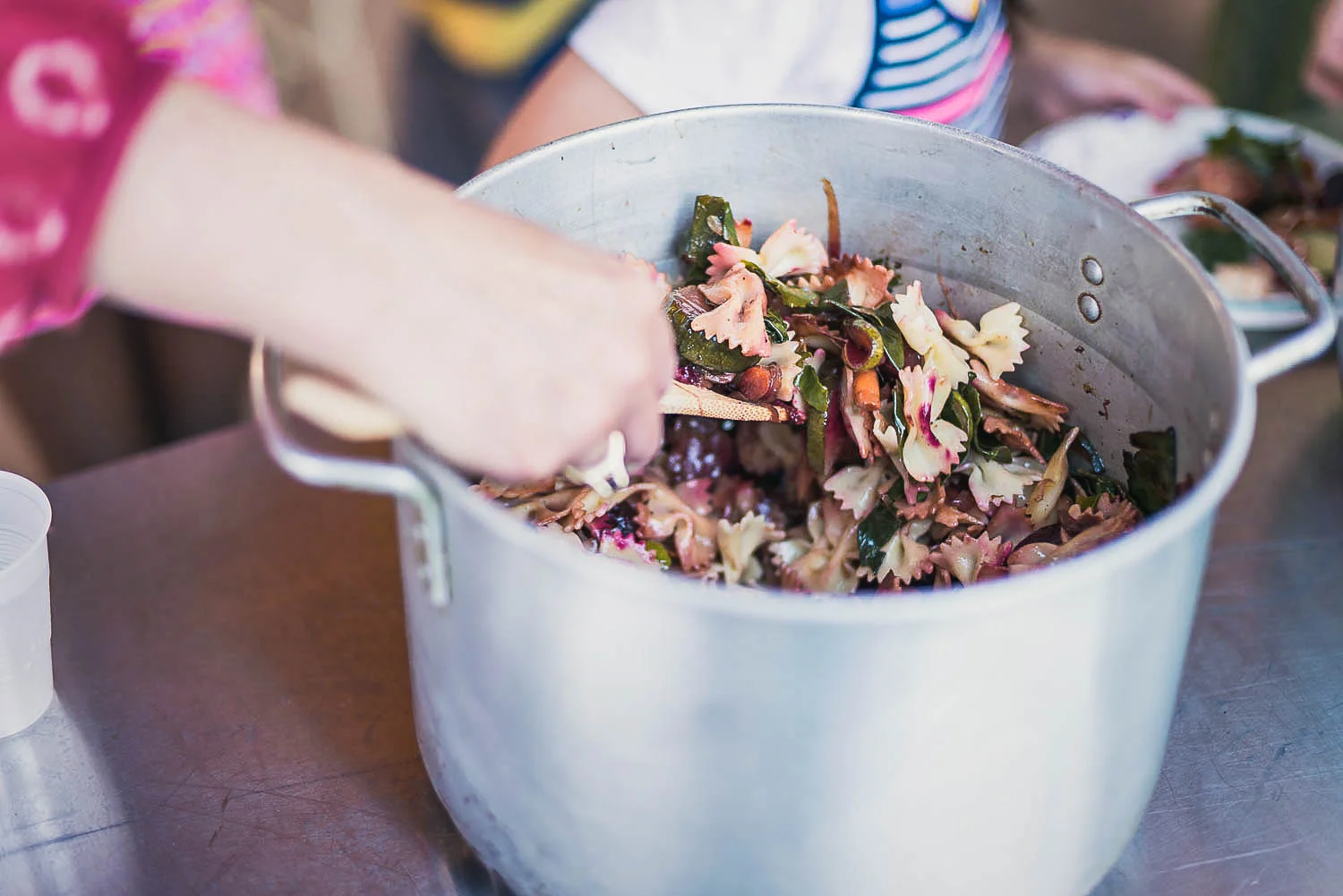 A visitor scoops bowtie pasta onto their plate during the July 19, family dinner at Common Good City Farm in Washington, DC.