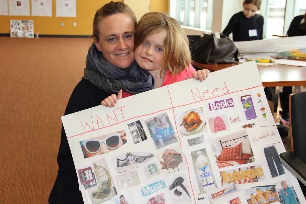 A mom and daughter share their "Needs vs. Wants" poster at Make It Count!