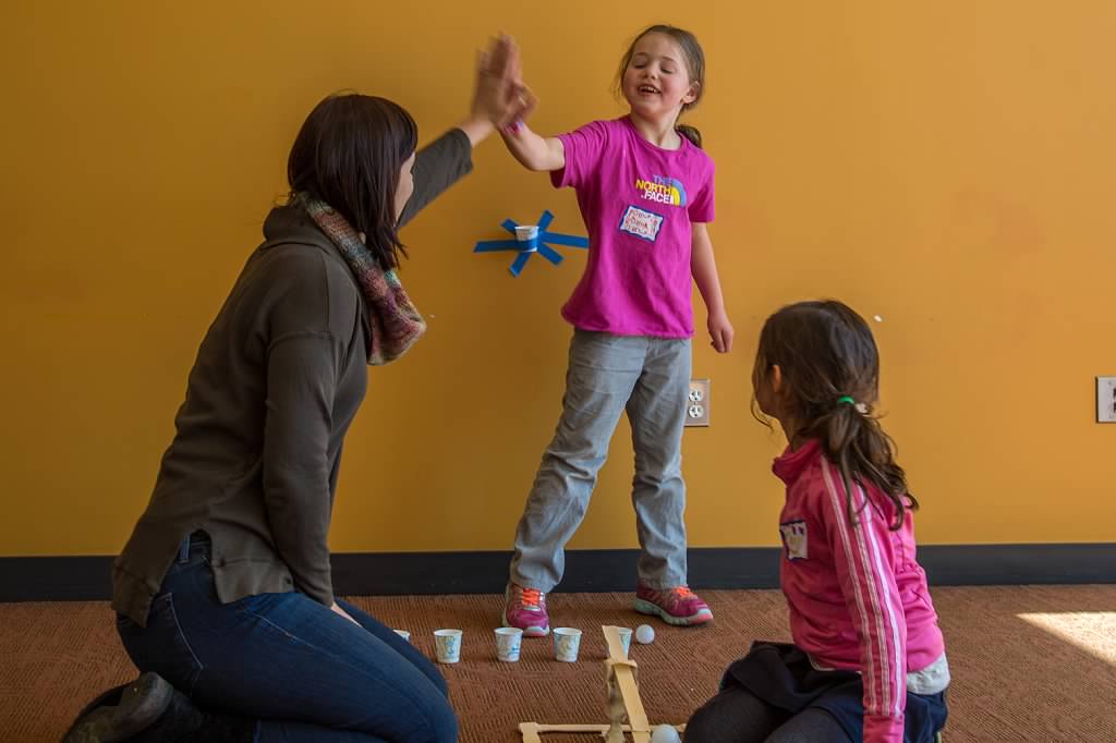 A mom and daughter slap-five after getting their ping pong ball launcher to work at our STEM program Build Bridges! Photo by Diane Hammer
