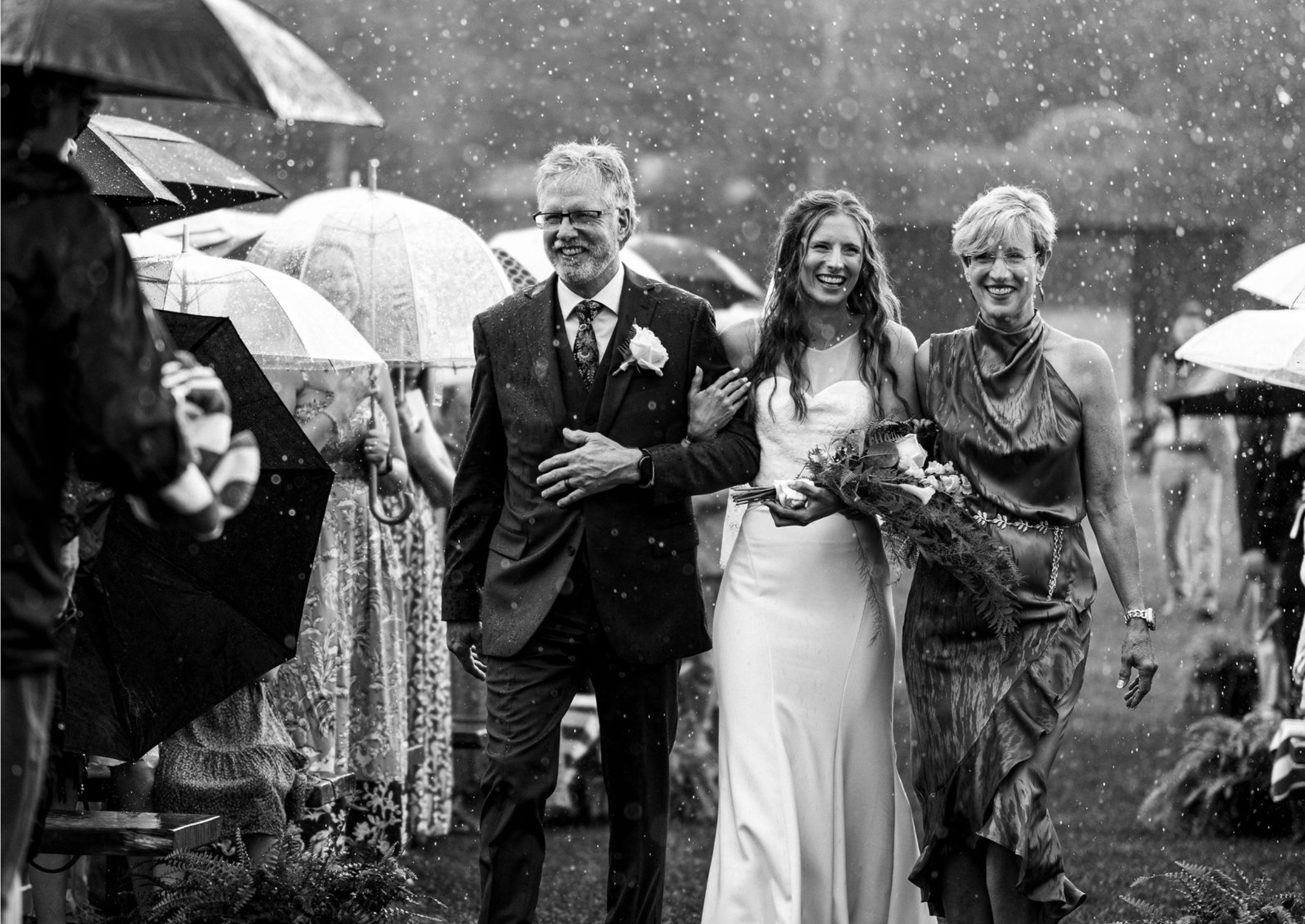 Mother and father walk bride down aisle in pouring rain during wedding at Mountain Top Inn, Vermont.