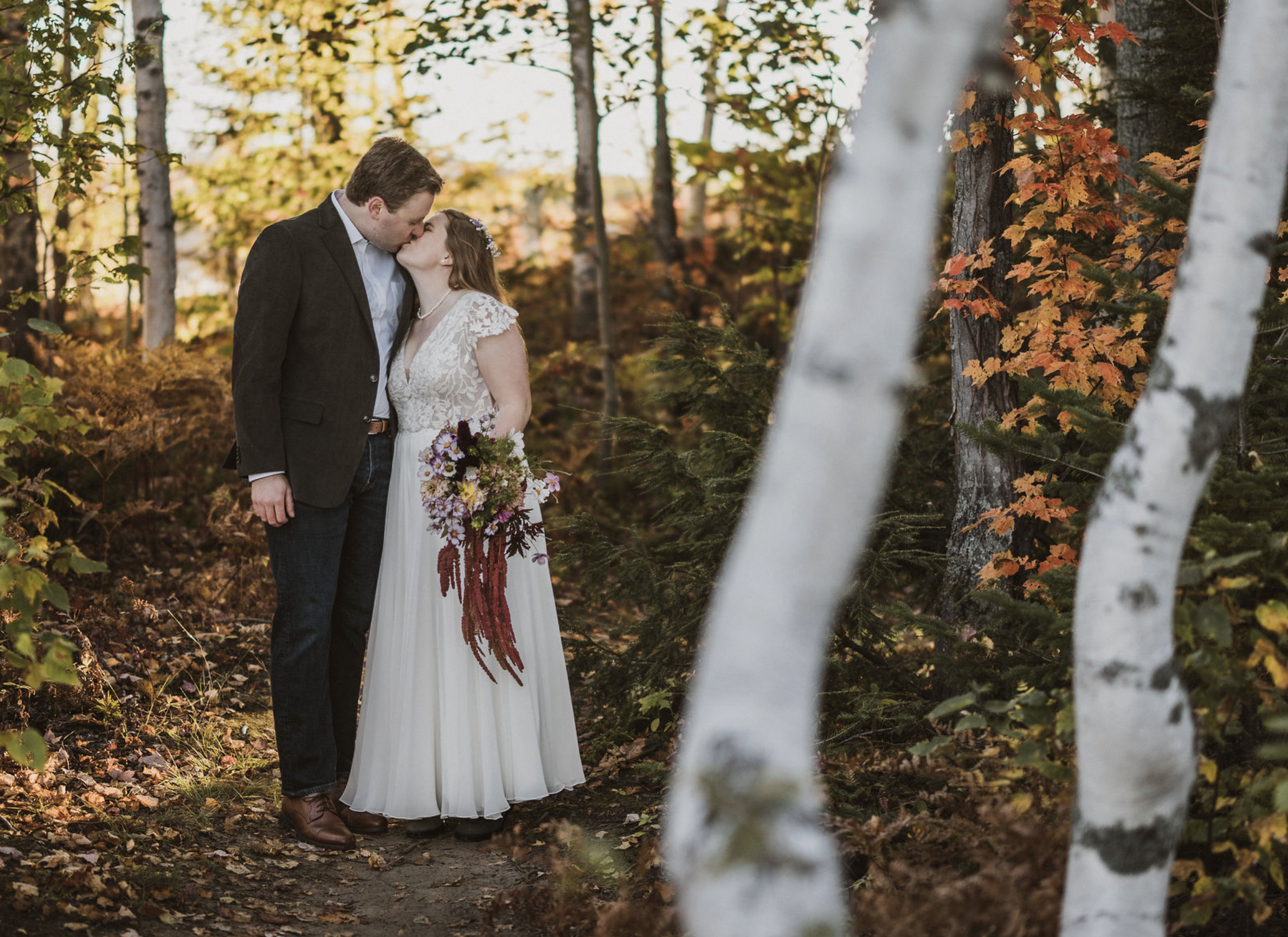 Couple kisses in a birch tree grove after getting married at Maine Huts and Trails