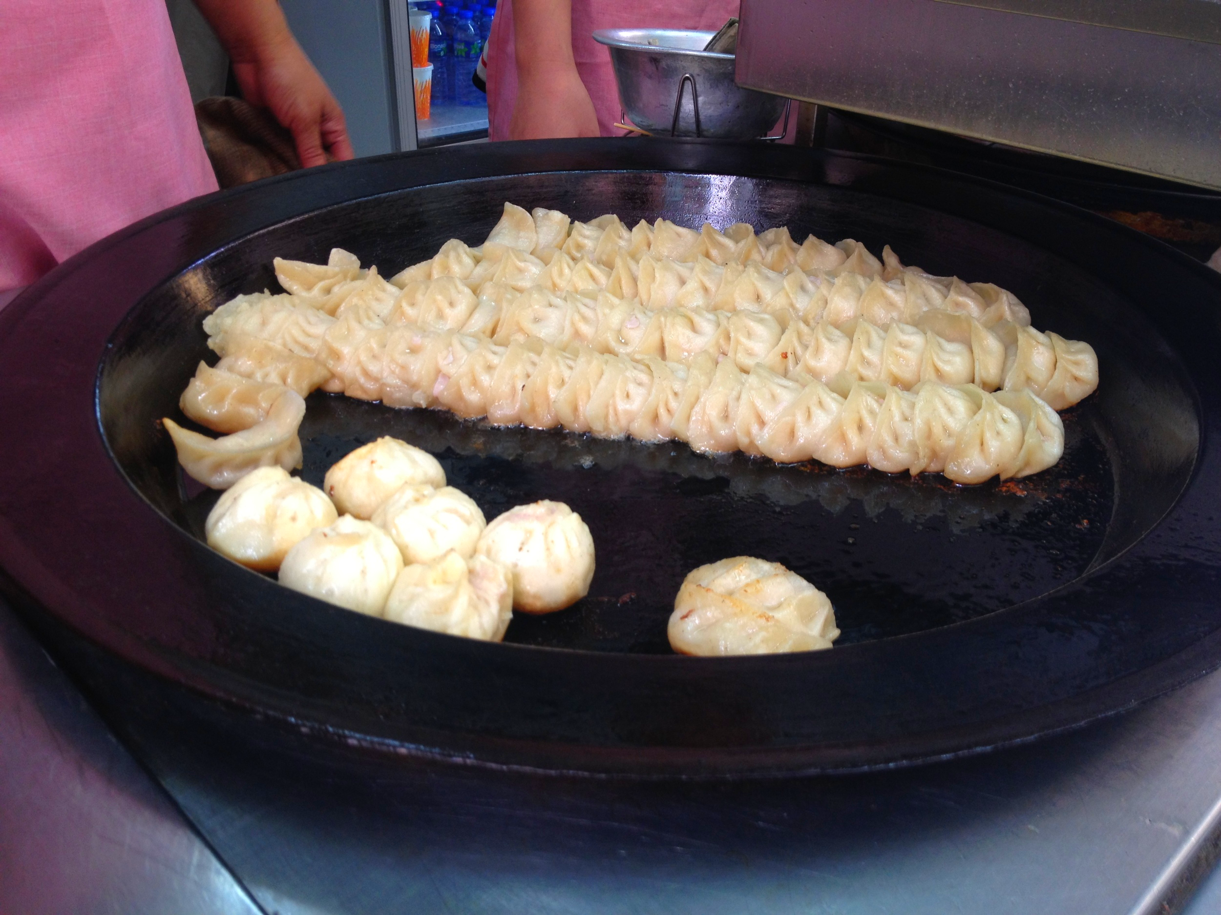 Boiled dumplings being seared on a steel plate