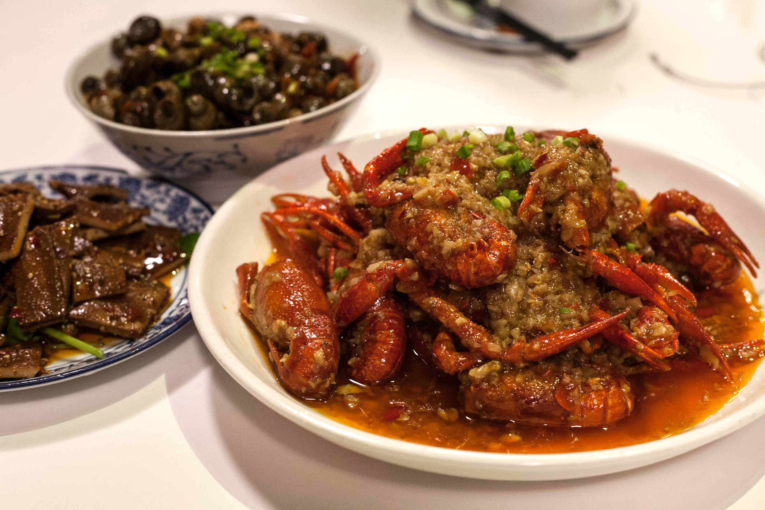 Clockwise from front - Stir-fried whole crawfish with garlic and chili served with smoked bean curd and sea snails
