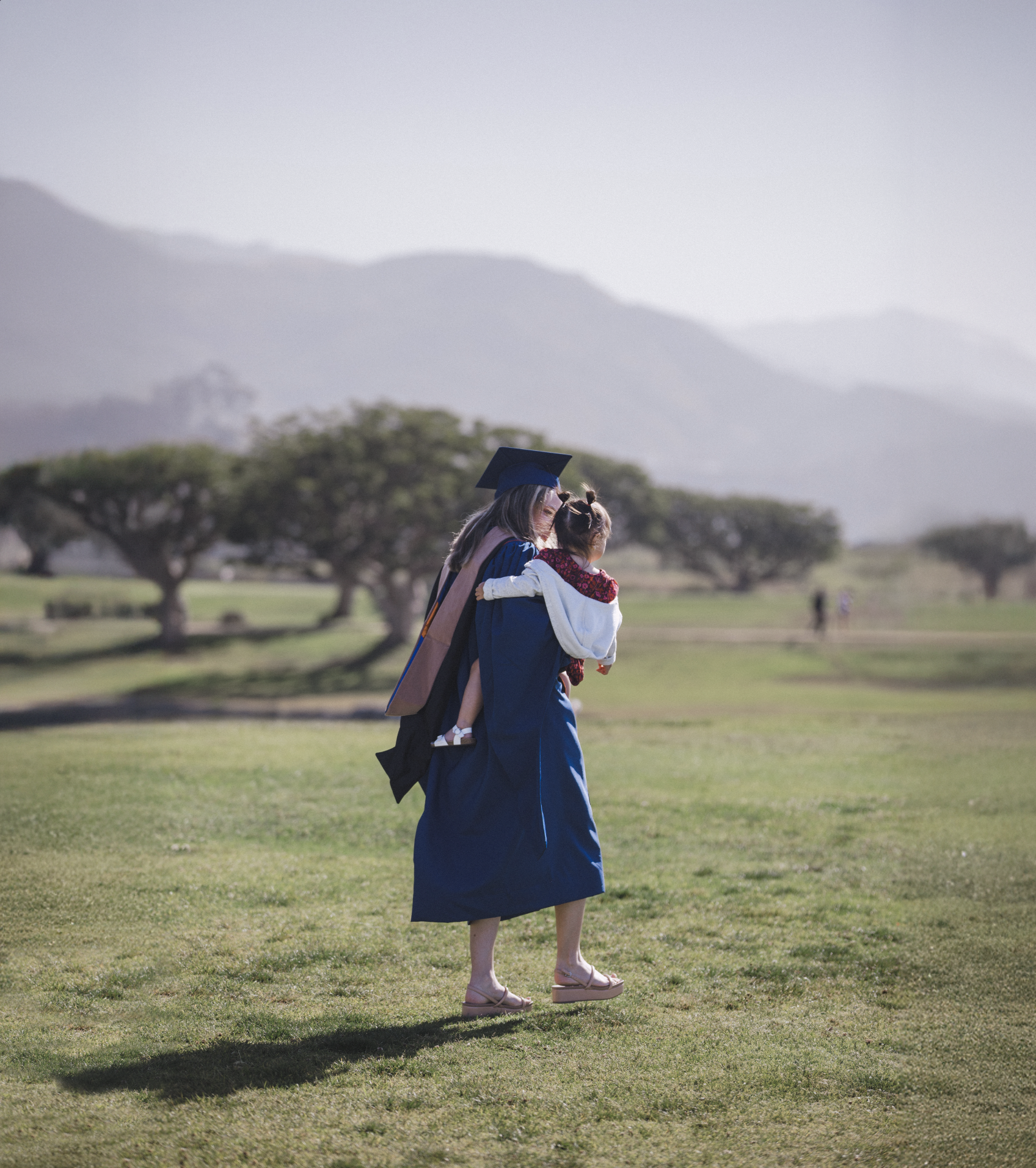 woman in graduation gown holding a toddler