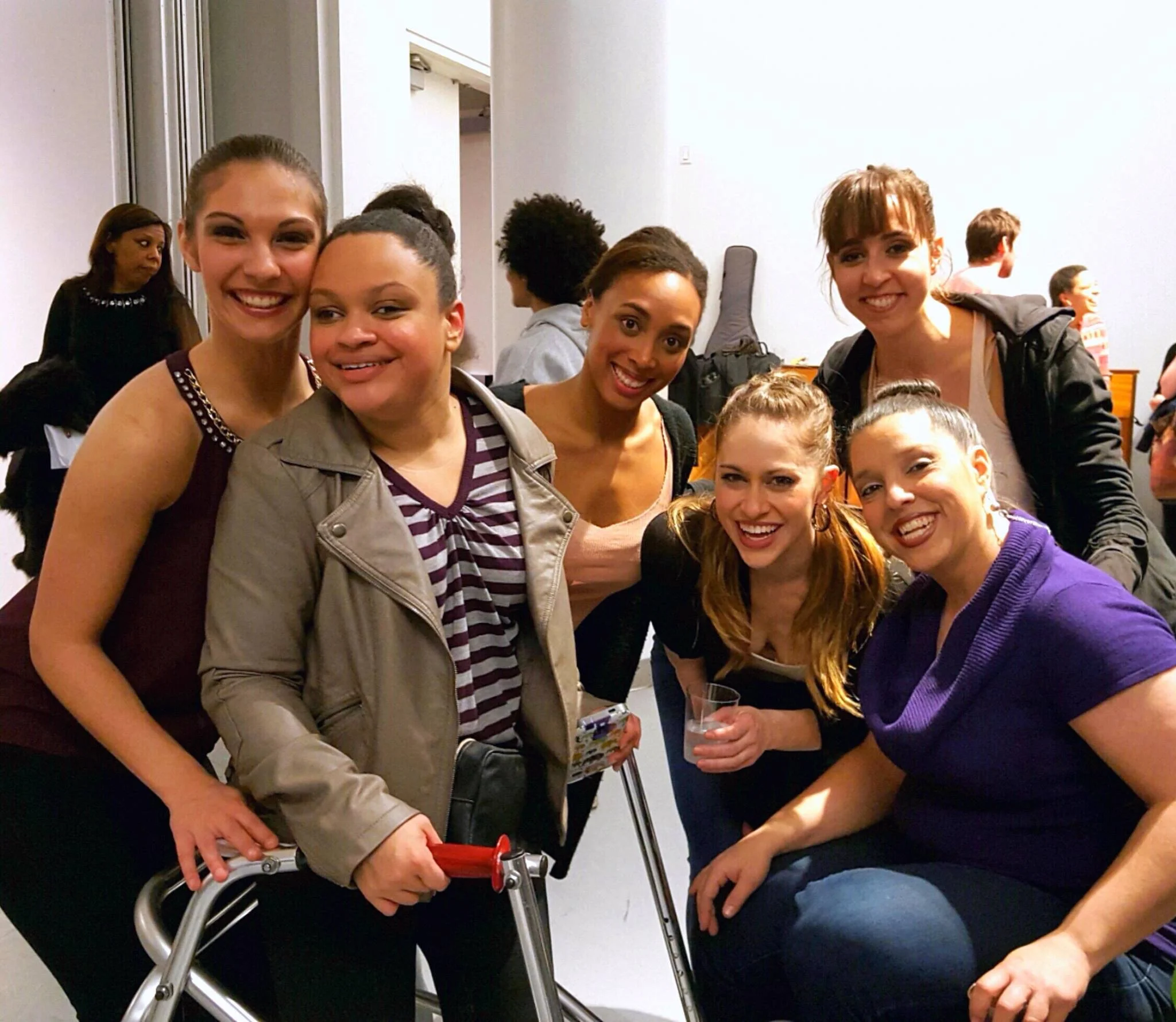 6 dancers in street clothes having fun and posing for the camera. Some use walkers or wheelchairs.