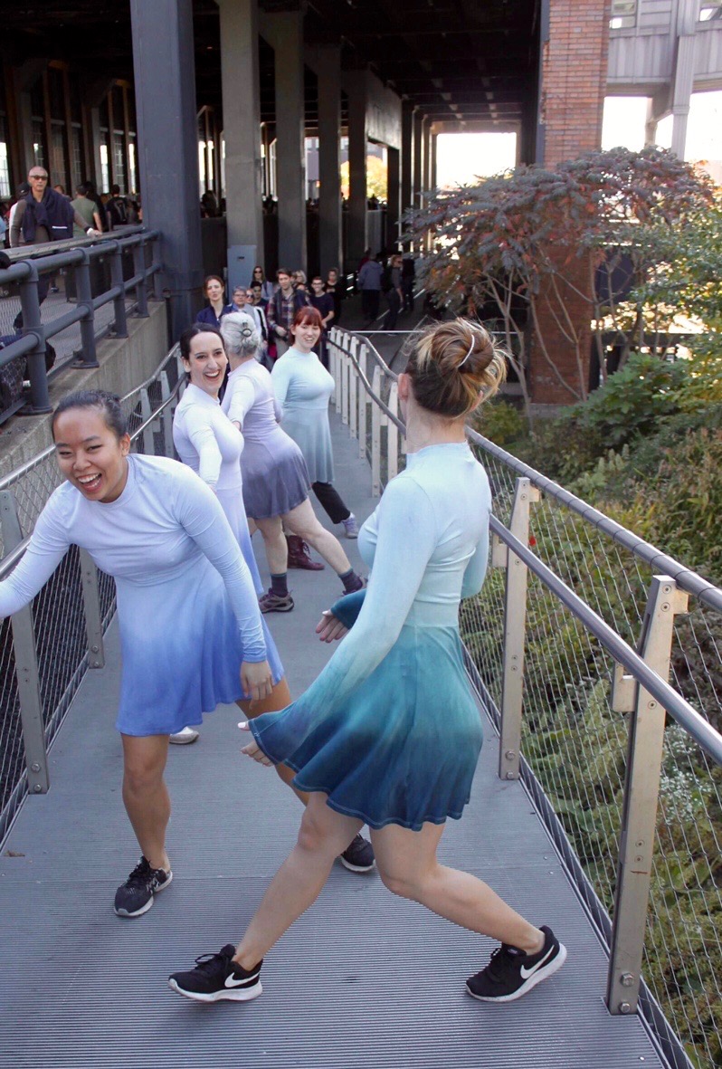 Group of dancers in two lines at a video shoot at the High Line cracking up and laughing.