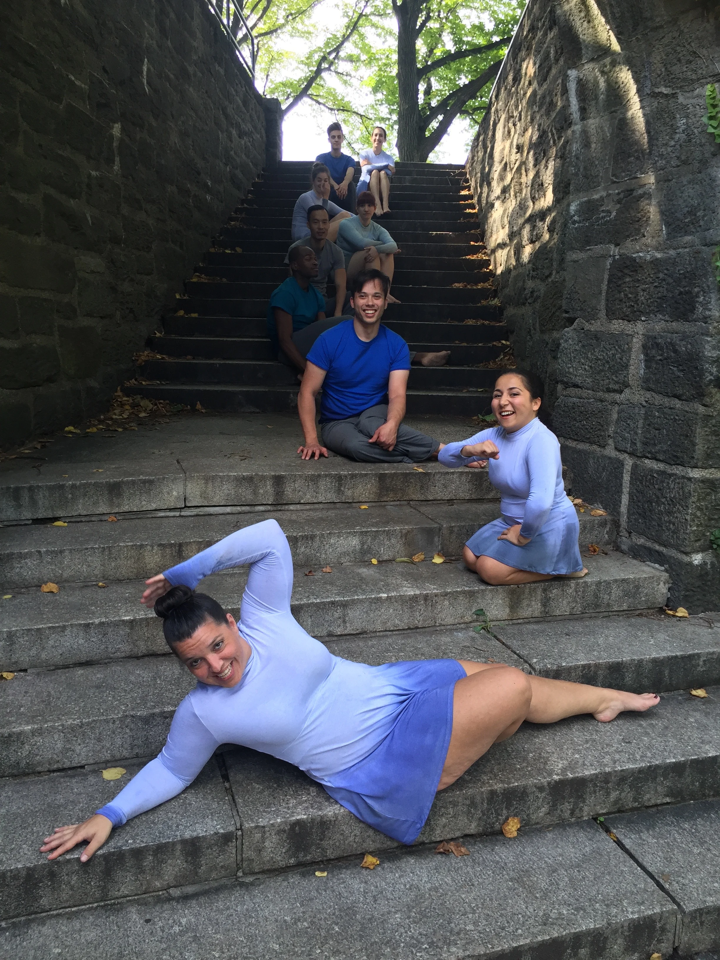 Dancers Jamie, Sofiya, Peter and others in blue costumes having fun on stairs at the Cloisters in New York City during outdoor video shoot.