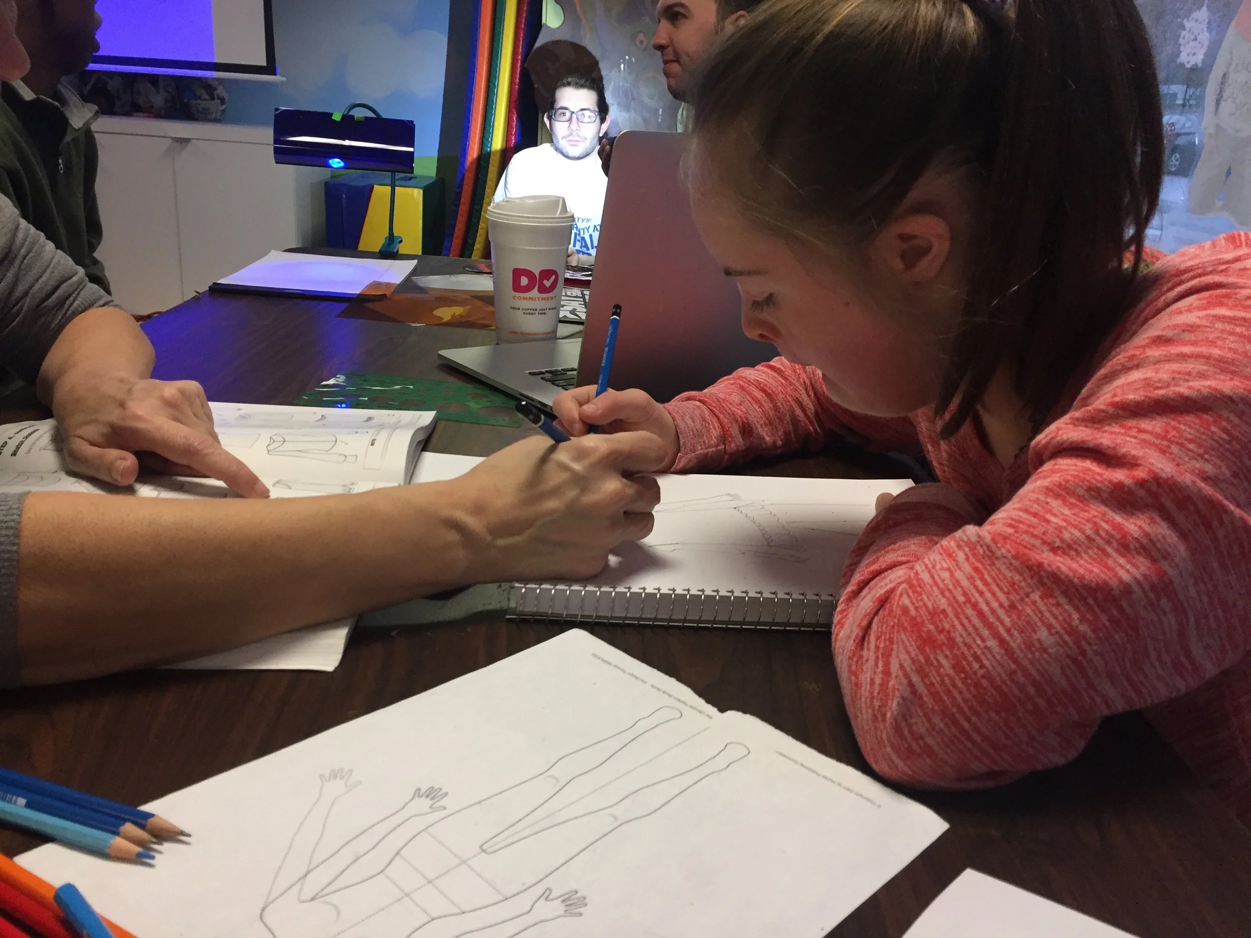 Production apprentice Charlotte drawing a costume sketch.