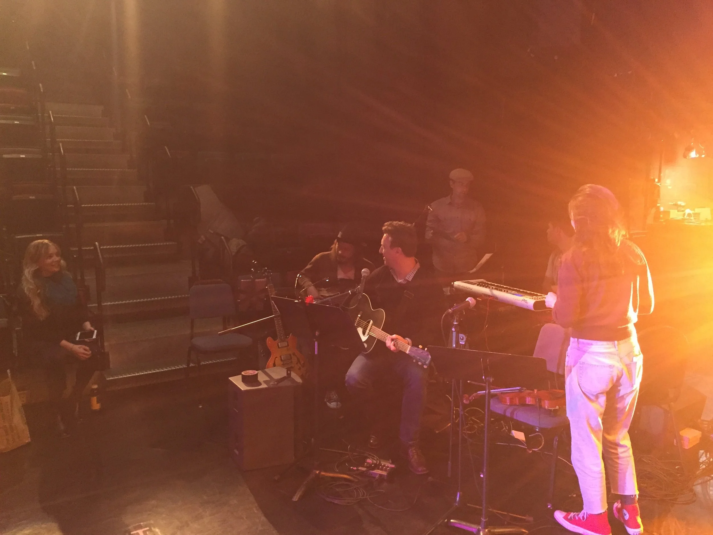Musicians at the theater getting their instruments set up and talking.