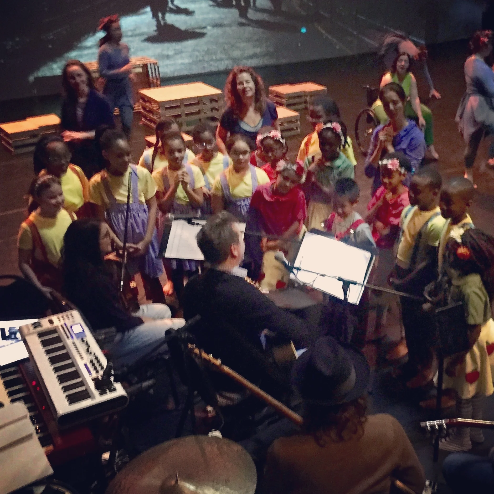 Large group of student-dancers talking to the musicians at the theater to learn what they do.