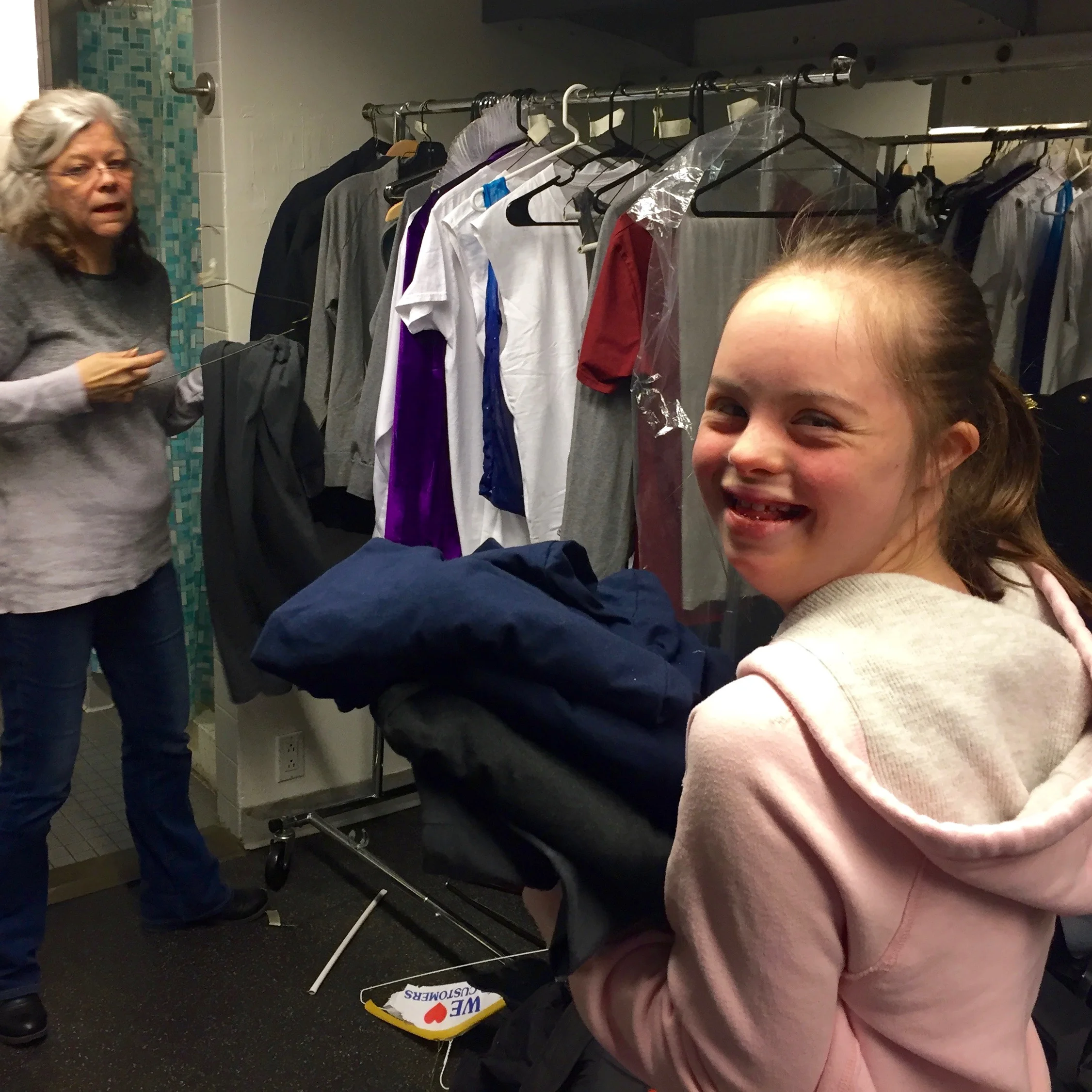 Costume apprentice Charlotte organizing and hanging costumes onto the rack with seamstress Kelly Hart.