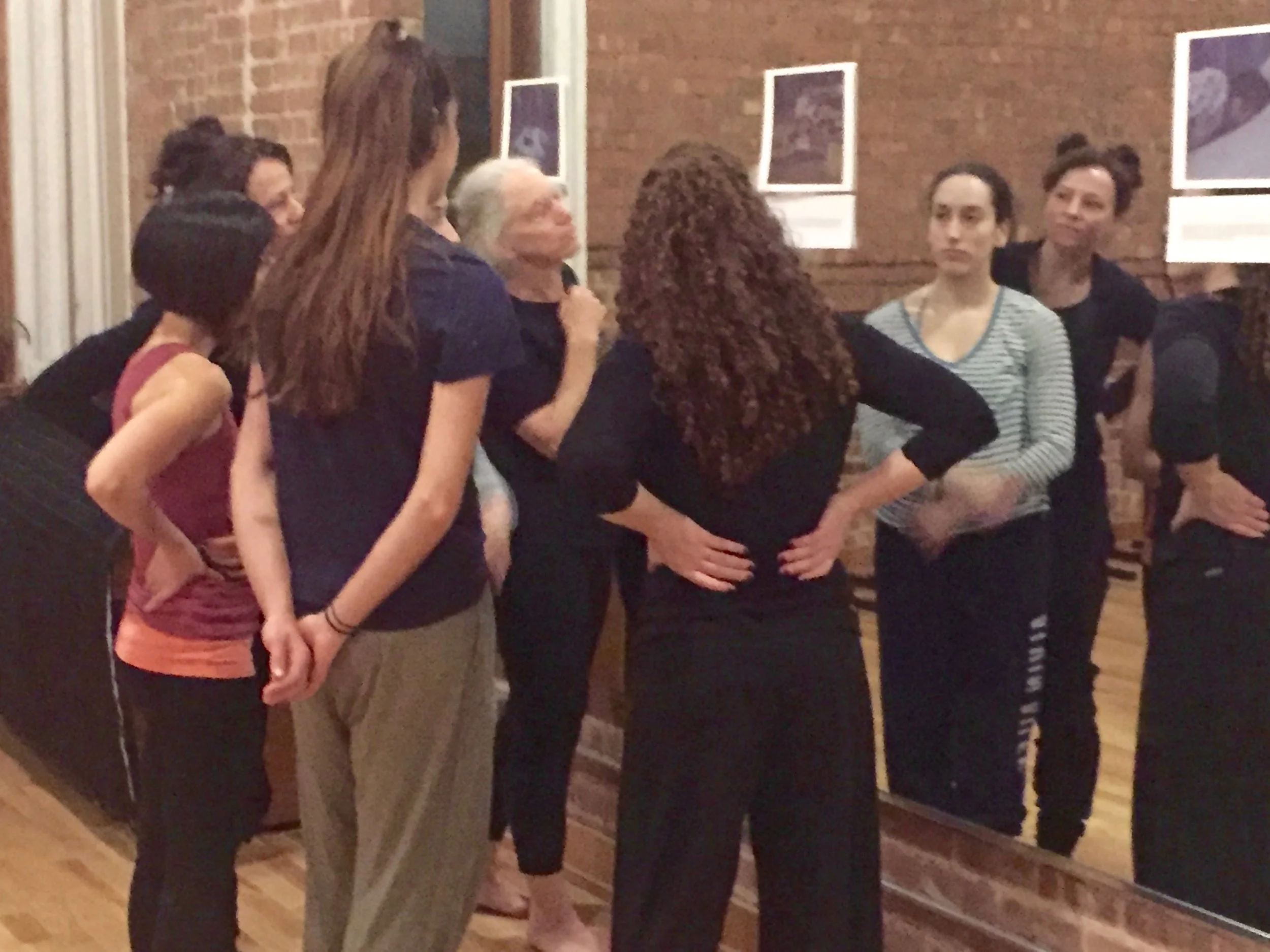 Small group of dancers in rehearsal looking at an image posted on the mirror.