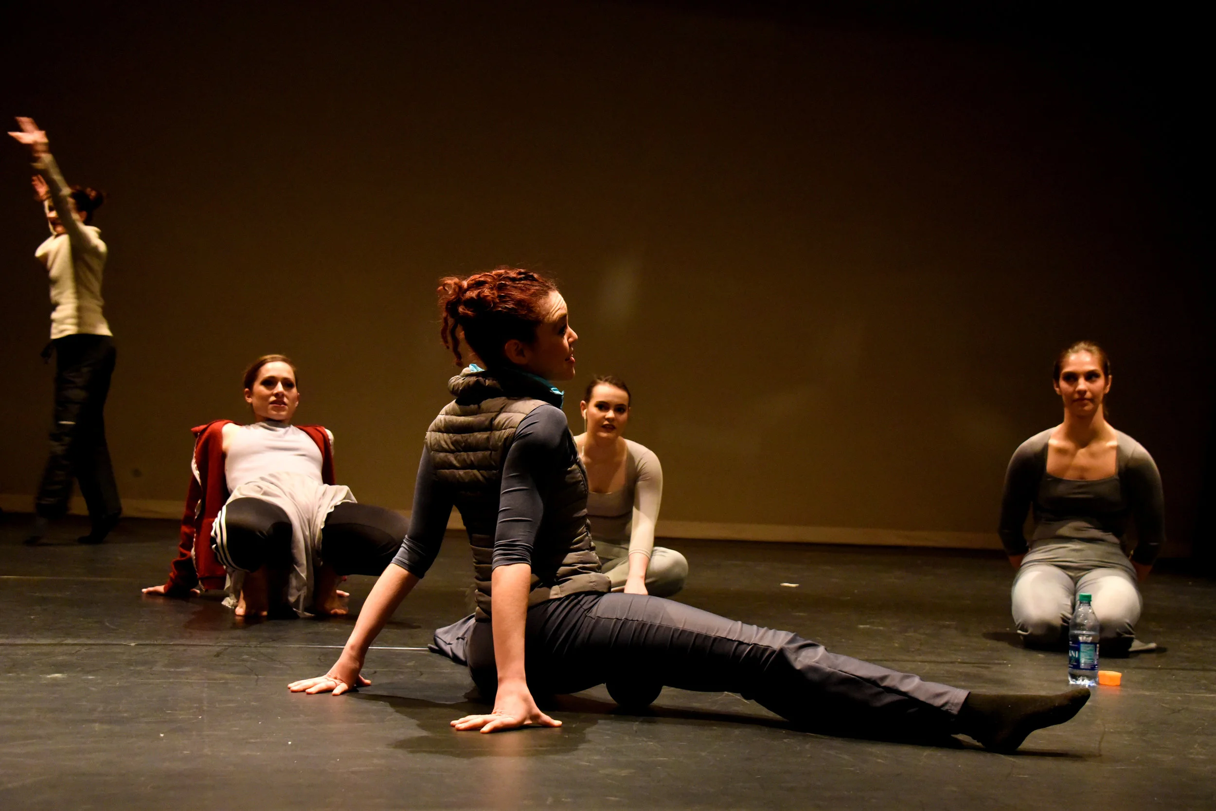 Five female dancers warming up on stage.