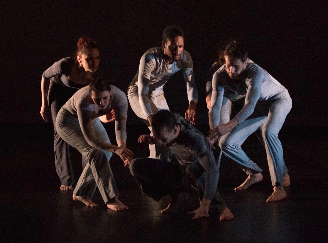 Grey. Male dancer is put on the floor by five other dancers.