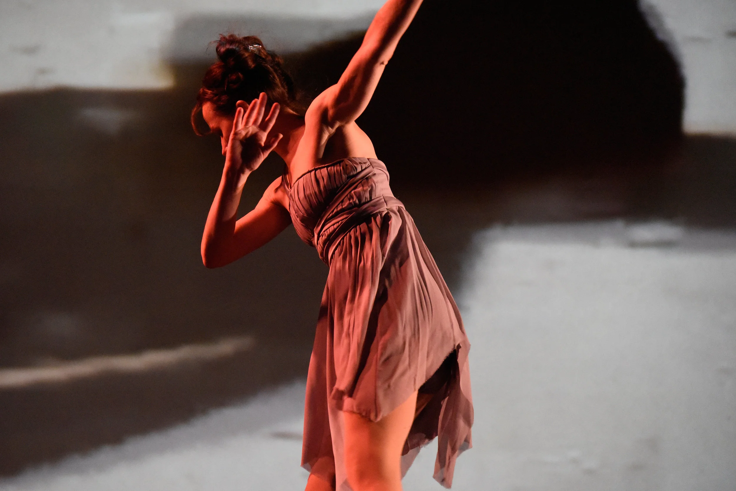 Grey. Dancer Nicole Speletic turns her face and upper body away and brings one arm up to the face as though shielding herself from something.