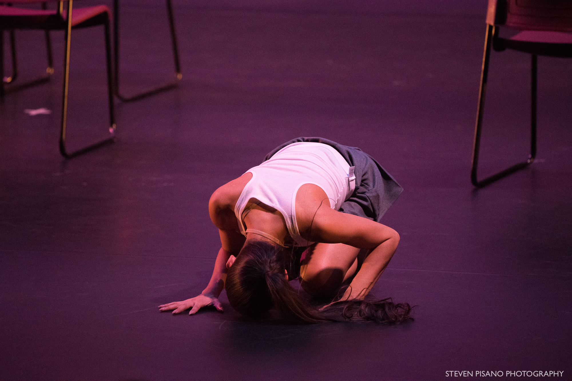 Sshhh. Close up of dancer Stefanie Roper who is folded forward into a small ball on the floor.