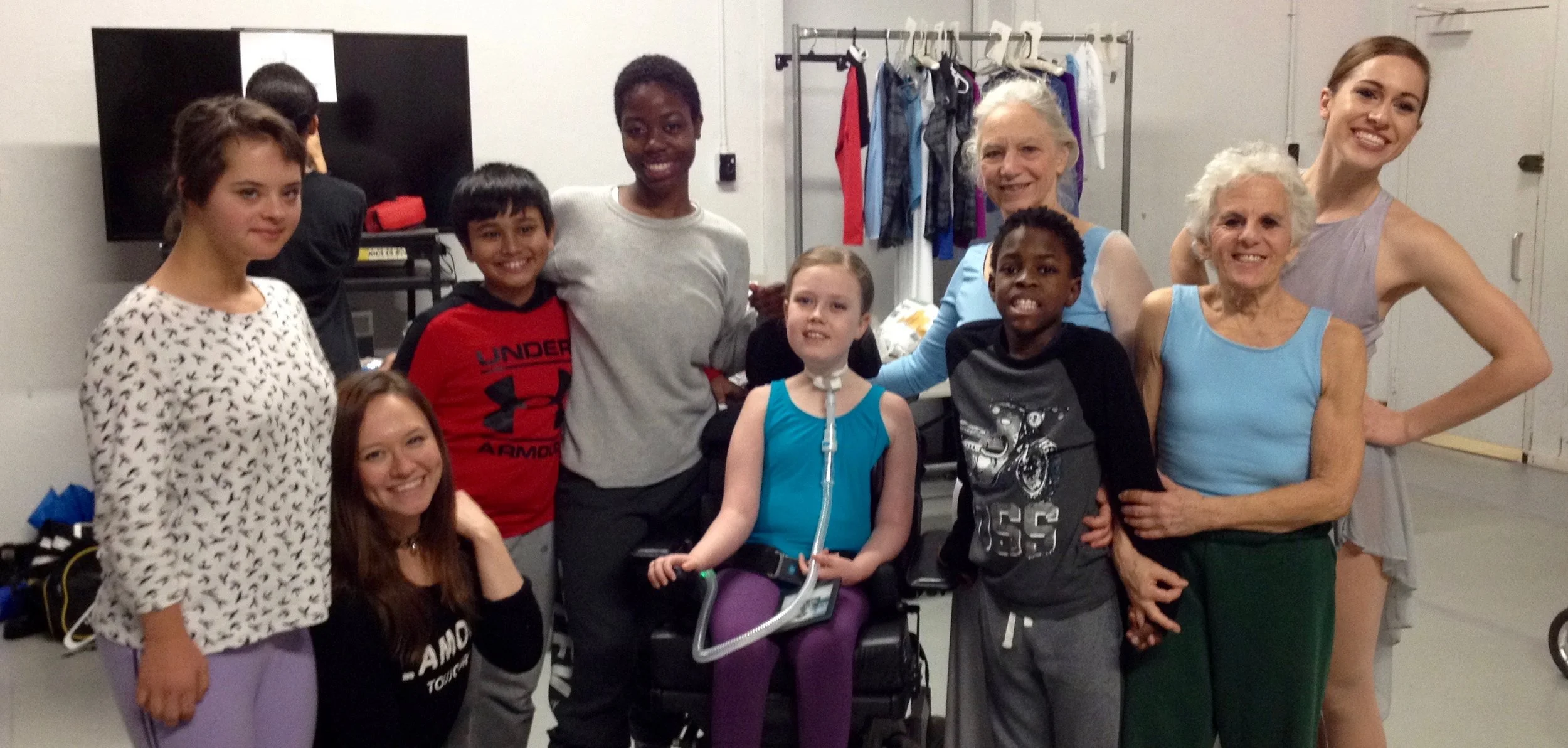 Four dancers, the Student-Coordinator, and four student-dancers posing and smiling for the camera in the dressing room.