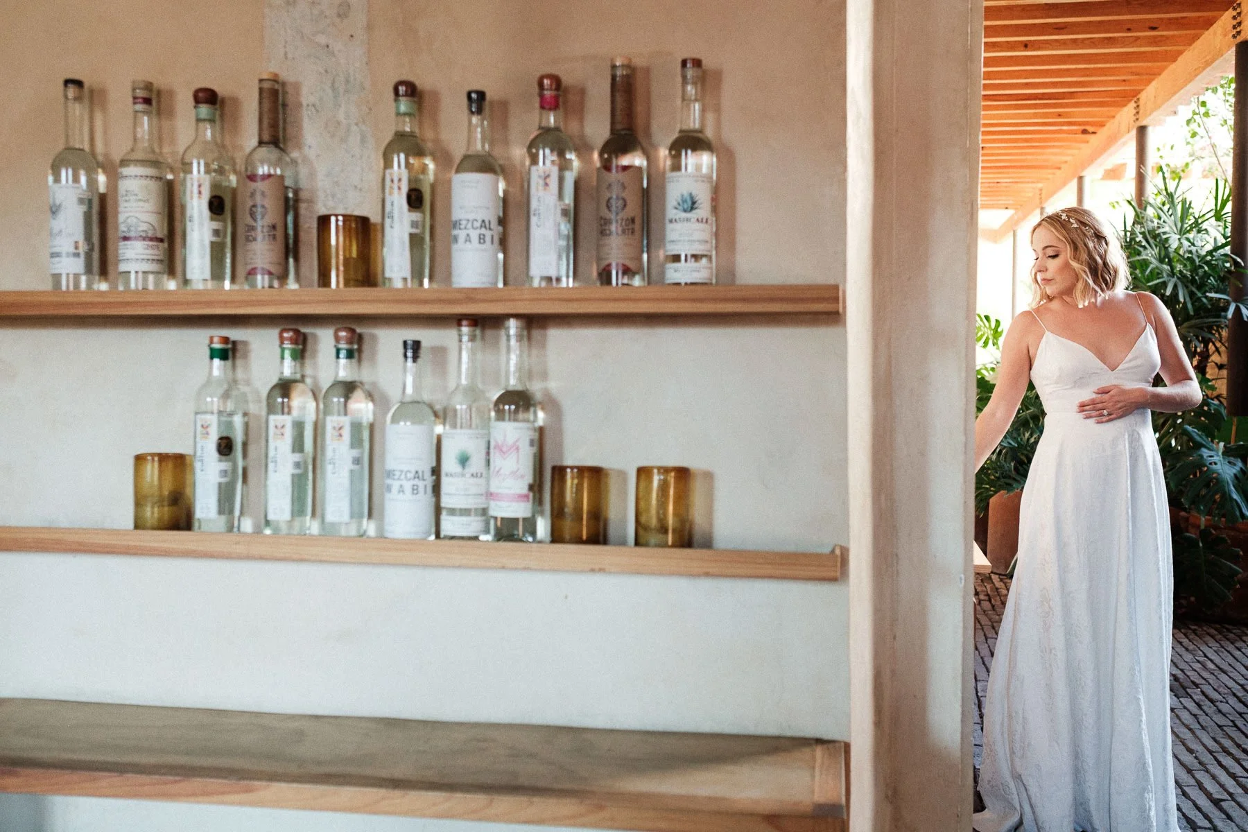 The bride framed by the iconic mezcal bottle wall during her getting ready at Hotel Escondido.