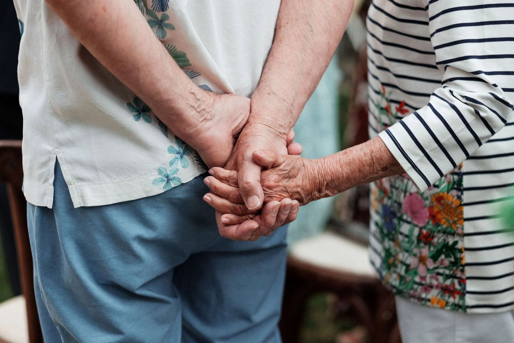 A tender documentary moment of the groom’s grandparents holding hands during the service.