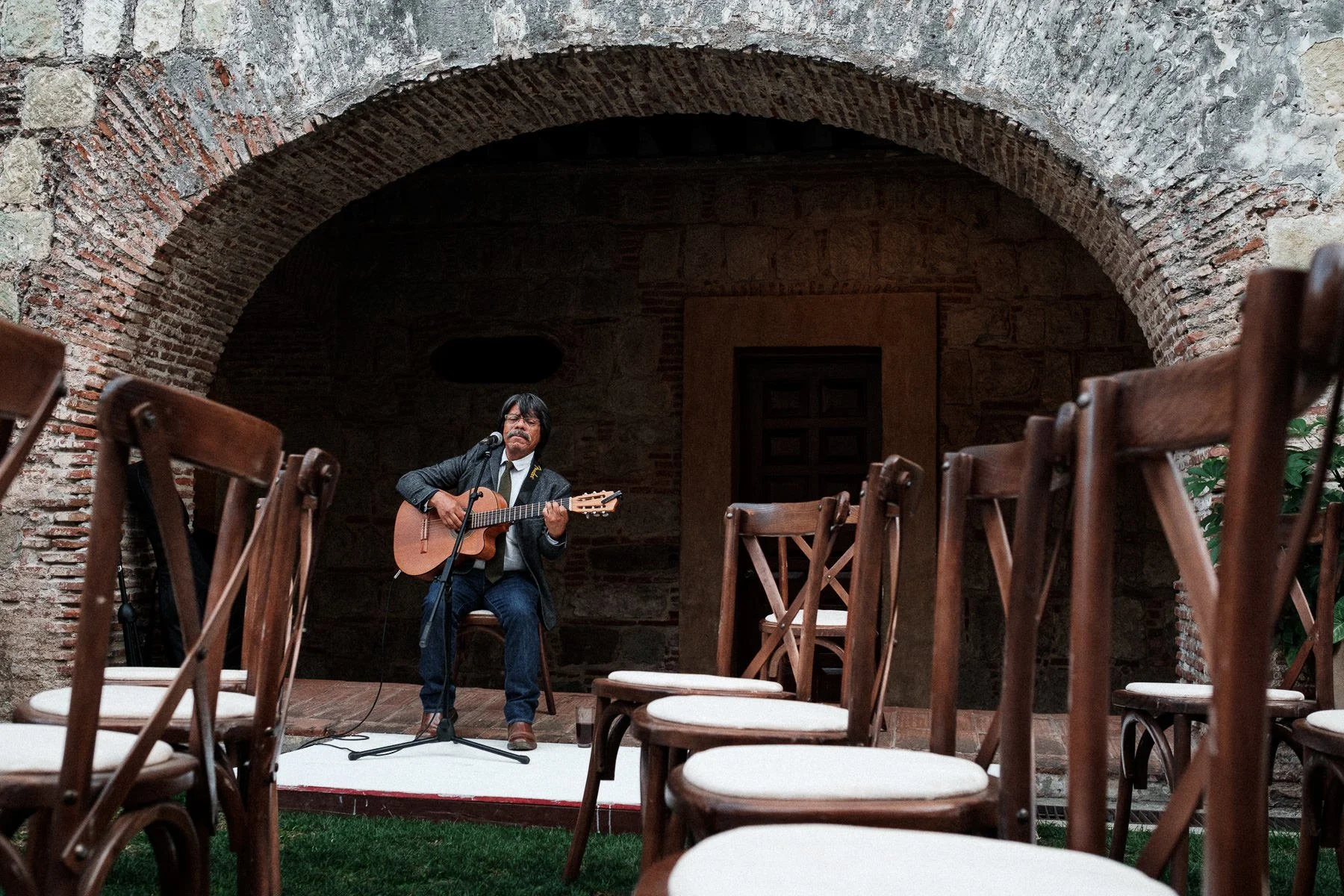 Street photography style: a lonely guitarist among empty ceremony chairs at Quinta Real.